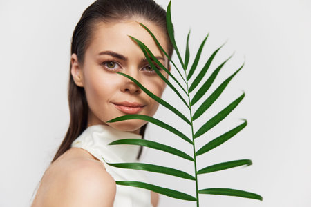 Portrait of a young woman with a tropical leaf, showcasing natural beauty and elegance, perfect for lifestyle and wellness themes.の写真素材