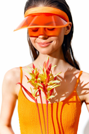 Vibrant summer fashion with a joyful model wearing an orange outfit and visor, holding colorful flowers, evoking a sunny vibe.の写真素材