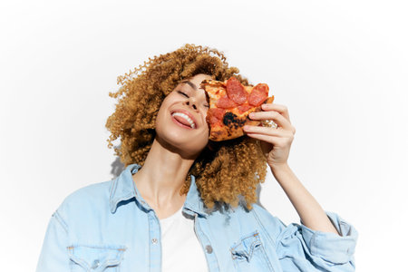 Happy woman with curly hair enjoying pizza, showcasing vibrant colors, fun emotions, and a minimalist white background in a casual styleの写真素材