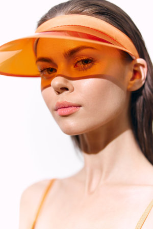 Young model with an orange visor, showcasing a fresh summer look and natural beauty, perfect for...