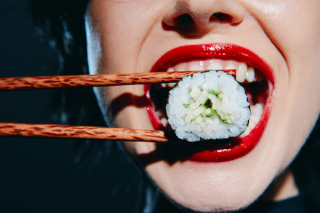 Woman enjoying sushi with red lipstick, highlighting a fun, vibrant dining experience with green...