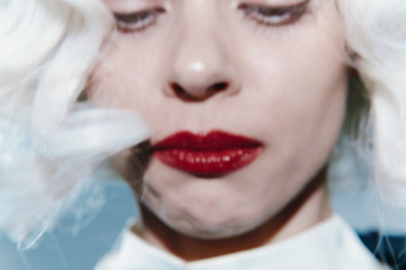 Elegant portrait of a model with platinum blonde hair, wearing a chic outfit, showcasing bold red lips, perfect for fashion and beauty concepts.の写真素材