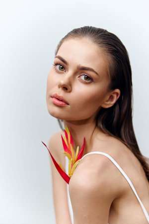 Portrait of a young woman with a flower, expressing serenity and grace in a soft, minimalist setting, perfect for beauty and fashion concepts.の写真素材
