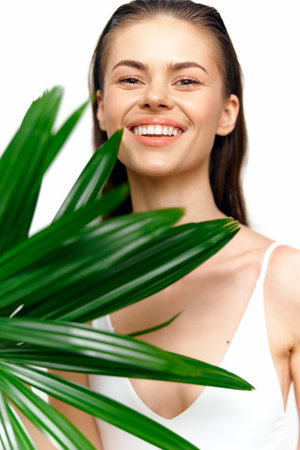 Cheerful young model with natural makeup and greenery background, showcasing joy and vitality in a bright summer setting.の写真素材