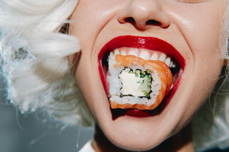 Bright and playful portrait of a woman with platinum blonde hair enjoying sushi, featuring bold red...