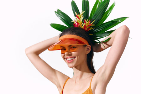 Smiling young model with tropical headwear, bright swimsuit, and a playful expression against a white background, ideal for summer and vacation themes.の写真素材