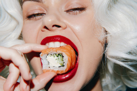 Young woman enjoying sushi with red lips and white hair against a bright background showcasing a...