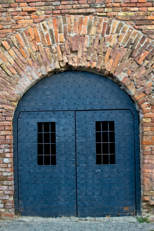 An old iron door in an old brick fortress wallの写真素材