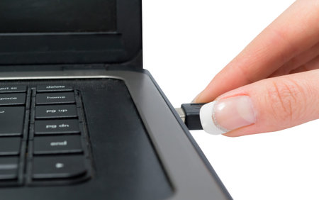 female manicured hand plugging the laptop with a usb on white background