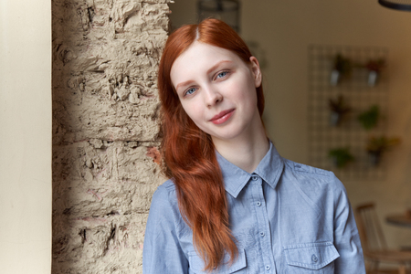 Pretty redhead young woman near the windowの写真素材