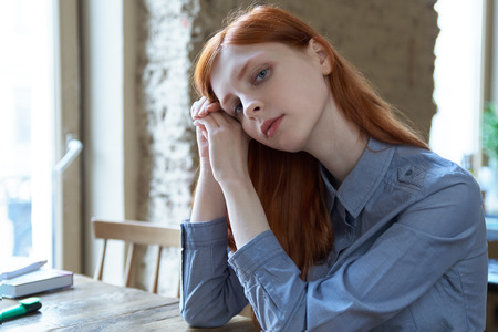 young red-haired girl student woman preparing for exams at the cafÃ©.の写真素材
