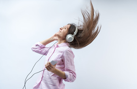 Beautiful young girl with headset on a white background smiling and her hair up in the airの写真素材