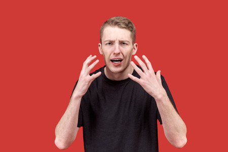 emotional young Caucasian man in a black t-shirt actively gesticulating hands with an indignant dissent expression. The concept of irritability, anger, indignation,の写真素材