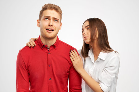 Beautiful woman calms down colleague man, who has troubles, miserable facial expressions, keeps...