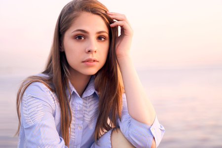 Portrait of young charming long haired woman with dark eyes, beautiful skin and full lips, sitting...
