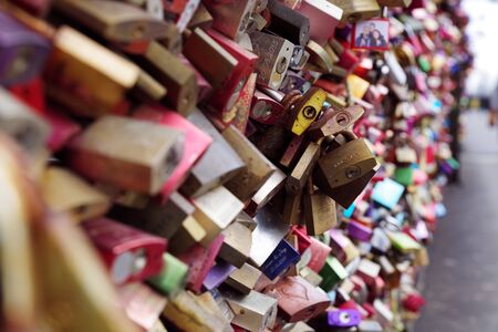 Tens colorful metal pad locks, love locks, with people names engraved, symbolizing eternal unbreakable love, relationship between two loving people. Famous city landmark of Cologne, Germany.の写真素材