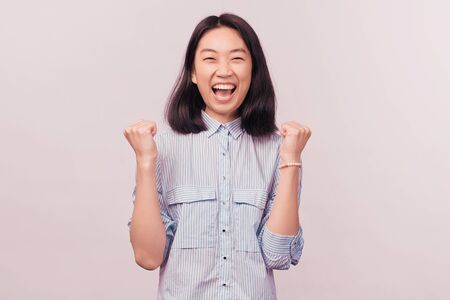 Portrait delighted girl raising fists shouting yesの写真素材