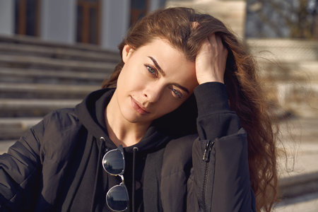 girl straightens curls, holding hand on head