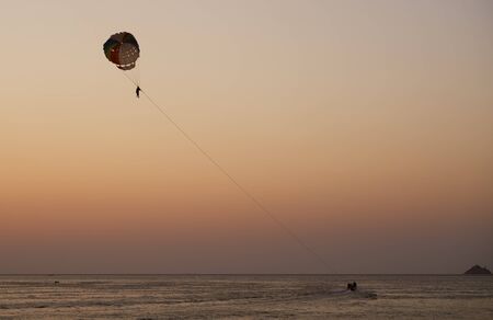 Silhouettes of people with parachute and boatの写真素材
