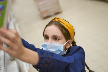 Girl makes stock of products. Reaching food shelf