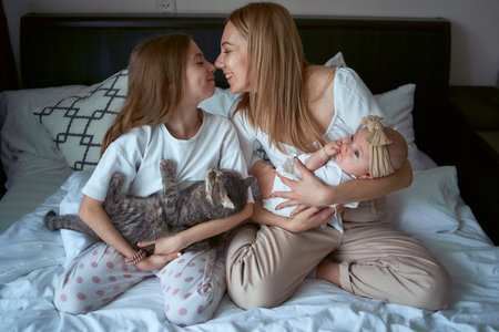 mother and two daughters plays with a catの写真素材
