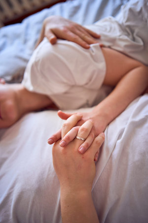 a young couple on the bed holding hands, a girl on a boy's shoulder, tender hugs and touches