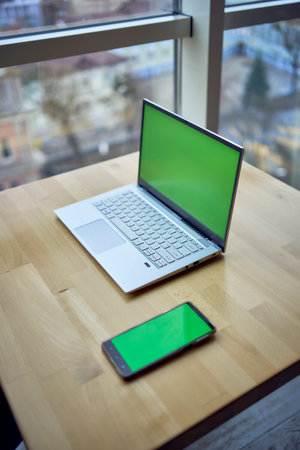a laptop and phone with green screen on single workplace table, chroma key,の写真素材