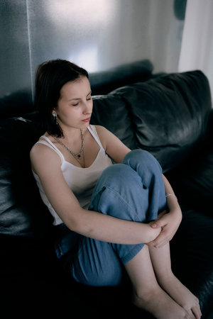 a young teenage girl fighting brain cancer at photo shoot in studio, metal wall, reflection, black sofaの写真素材
