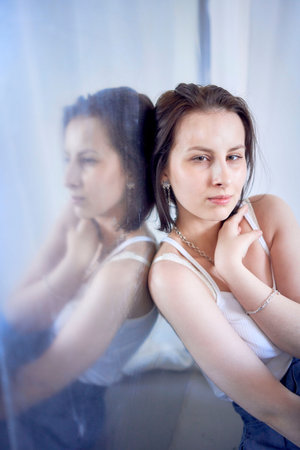 a young teenage girl fighting brain cancer at photo shoot in studio sitting on floor, leaning against metal wall, reflectionの写真素材