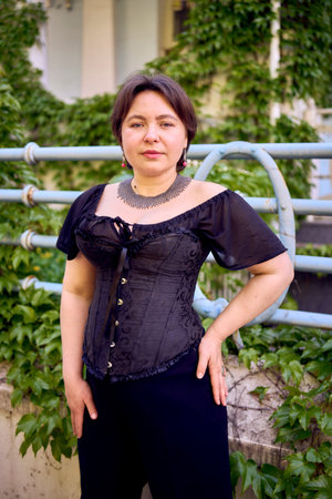 medium size woman in a black corset and wide leg trousers walks through the city in the morning...