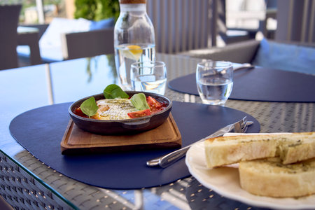 a medium sized woman in peach fuzz dress eating Shakshouka in modern restaurantの写真素材