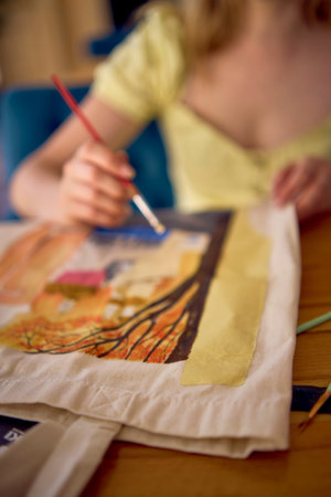 beautiful young artist in a yellow dress paints a customized shopping bag
