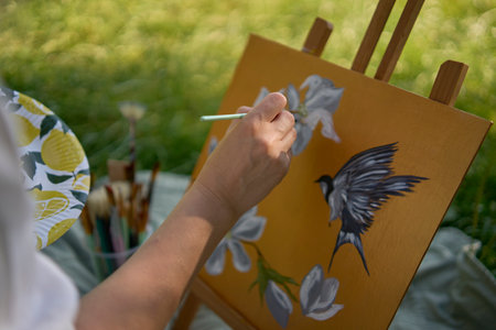 beautiful young artist in a white dress paints a picture on the river bankの写真素材