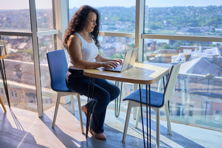 57-year-old woman works on a laptop in a modern office workspace