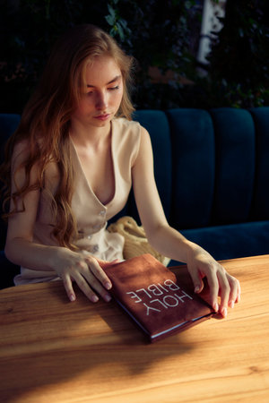 a beautiful teenage girl in a peach fluffy suit with a waistcoat in the old money  style reads the...