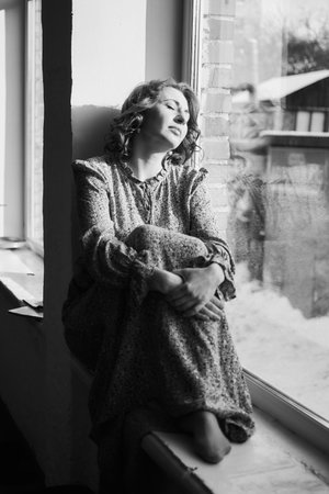 dreamy middle-aged woman by the windowの写真素材