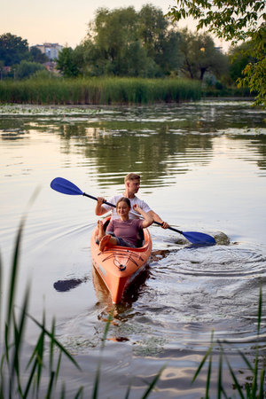 couple in love kayaking on the river at sunset