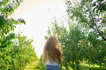 portrait of a teenage girl with long blond hair in a sunlit garden