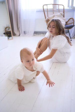 photo session on the first birthday of a baby girl with her  teenage sister, in pastel colors, minimalismの写真素材