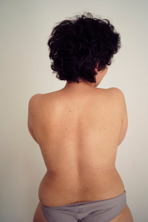 a young plus size woman topless in panties from the backの写真素材