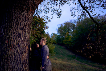 two 15-year-old teenagers in love under an old majestic oak in an autumn parkの写真素材