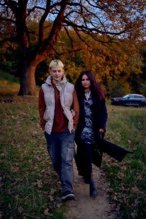 A 15-year-old teenage couple in love walks through the park on a cold autumn eveningの写真素材