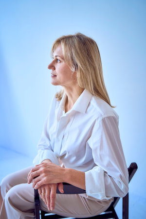 a  portrait of a stylish blonde middle-aged woman in a white blouse and beige pantsの写真素材
