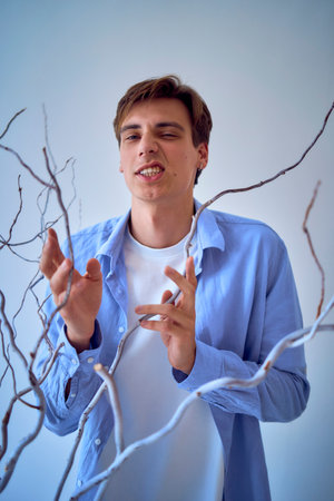 A  teenage boy posing dramatically with dry branches on a white backgroundの写真素材