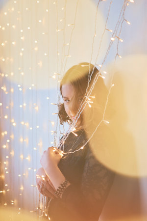 teenage girl in a dress surrounded by golden Christmas lightsの写真素材