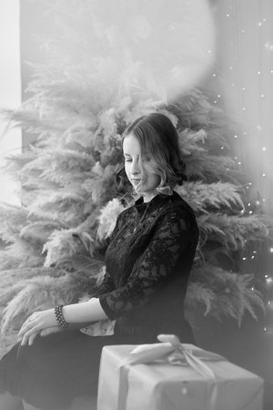 a teenage girl in a dress near an unconventional Christmas tree surrounded by golden lights
