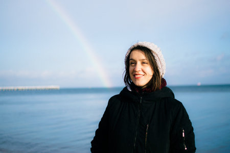 young woman rejoices at the rainbow on the embankment of Gdynia on a sunny winter day