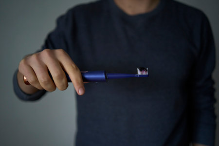 30-year-old man brushes his teeth with purple toothpaste using an electric toothbrushの写真素材