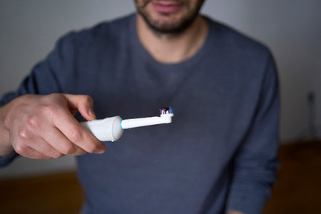30-year-old man brushes his teeth using an electric toothbrushの写真素材