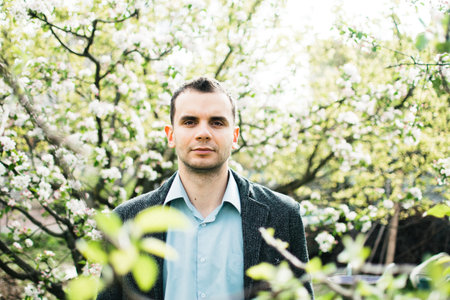 portrait of a man in a jacket and shirt in apple blossomの写真素材